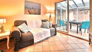 A cozy living room with a sofa, a table, and chairs, a lamp, and a large window with a view. - Stunning  villa for 4 people with WIFI, TV, terrace and pets allowed (Saint-denis-d'oléron)