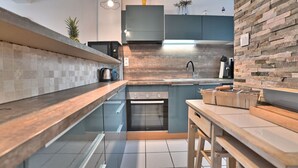 Eine moderne Küche mit einer Stein-Spritzschutzwand, einem eingebauten Backofen und einer Holzarbeitsplatte.