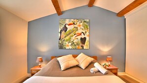 Ein Schlafzimmer mit Bett, Kissen, Nachttisch, Lampe und einem Bild an der Wand.