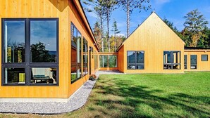 Et moderne træhus med store vinduer og en velholdt græsplæne.