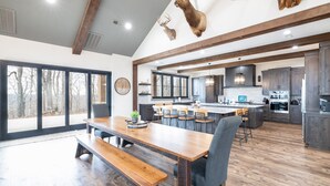 Een ruime keuken met houten kastjes, een groot eiland en een eethoek met een houten bank en stoelen.