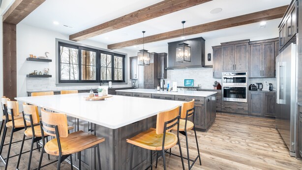 Een moderne keuken met een groot eiland, houten stoelen en inbouwmeubels.