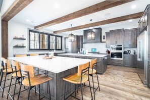 A modern kitchen with a large island, wooden chairs, and built-in cabinets. - Scenic River Front Lodge With A Fire Pit And Outdoor Kitchen (Marion)