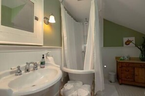 A bathroom with a sink, mirror, shower curtain, and a wooden cabinet. - Central Charleston Craftsman (Charleston)