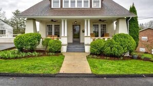 A two-story house with a front porch, a covered entryway, and a small front yard with trimmed bushes. - Central Charleston Craftsman (Charleston)