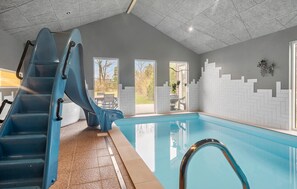 A swimming pool with a blue slide, a tiled floor, and a view of the outdoors. - Stunning home in Skjern with sauna (Skjern)