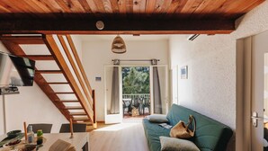 A cozy living room with a wooden staircase, a green sofa, and a dining area with a table and chairs. - Lovely apartment for 6 guests with A/C, pool, WIFI, terrace, pets allowed and panoramic view (Tarco)