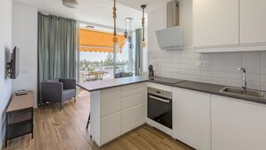 A modern kitchen with white cabinets, a built-in oven, and a large window with a view. - Stunning  villa for 4 guests with pool, WIFI, A/C, TV, terrace and pets allowed (Playa Del Ingles)