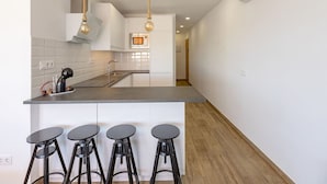 A modern kitchen with a central island, bar stools, pendant lights, and an air conditioning unit. - Stunning  villa for 4 guests with pool, WIFI, A/C, TV, terrace and pets allowed (Playa Del Ingles)