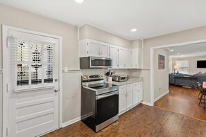 A kitchen with white cabinetry, a stainless steel oven, a microwave, and a toaster.