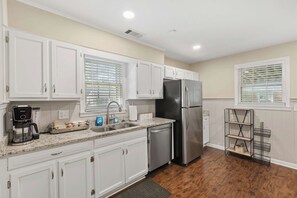 A modern kitchen with white cabinets, stainless steel appliances, and a granite countertop.