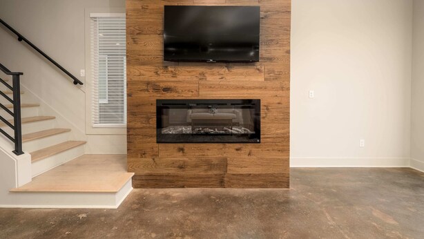 Ein modernes Wohnzimmer mit einer Wand in Holzoptik, einem Flachbildfernseher und einem Kamin.