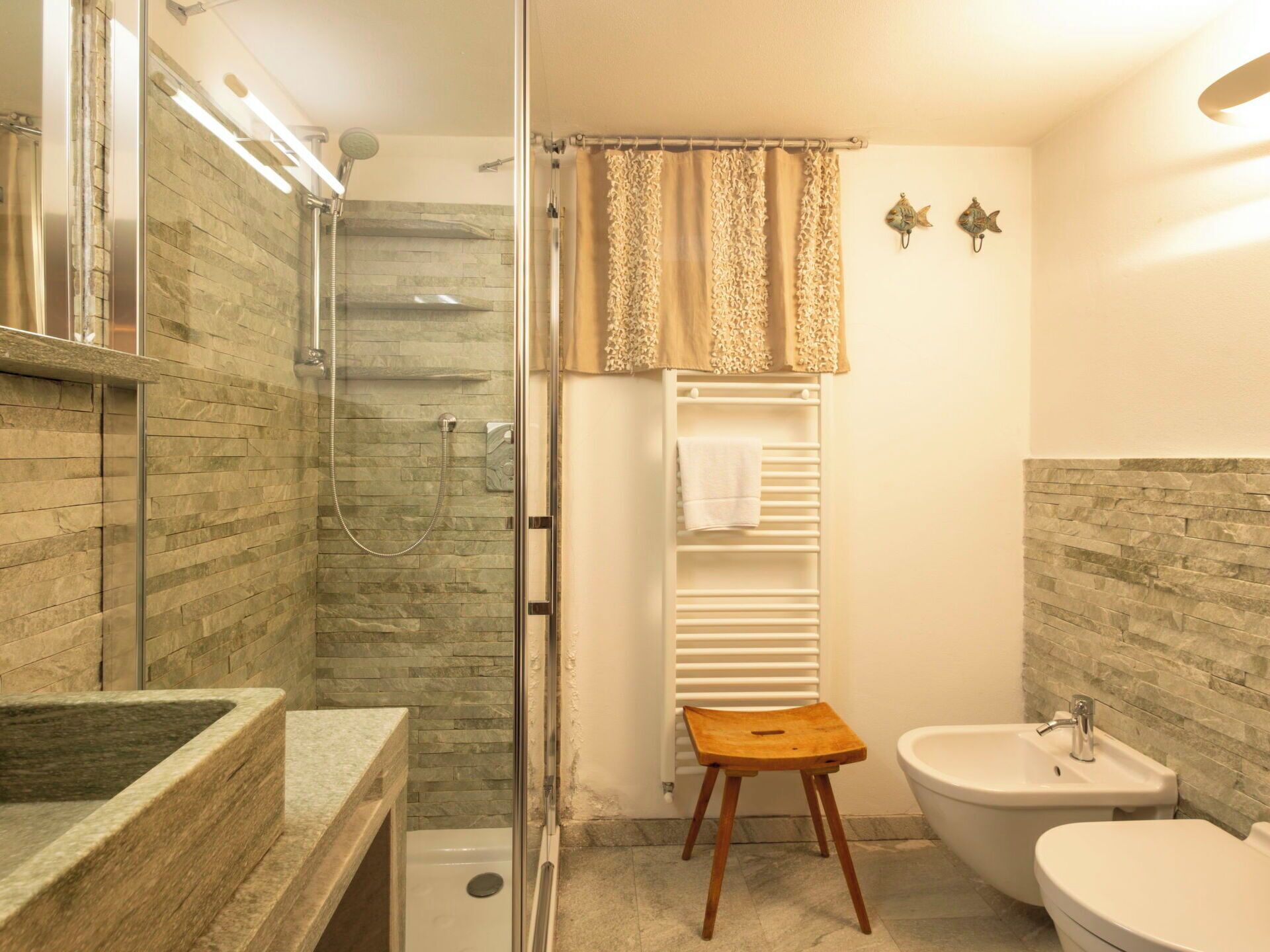 Une salle de bain avec une douche à parois de verre, un lavabo, un bidet et un porte-serviettes.