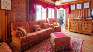 A cozy living room with a patterned sofa, ottoman, and a wooden cabinet. - Beautiful private villa for 9 guests with hot tub, WIFI, TV, balcony and pets allowed (Madesimo)