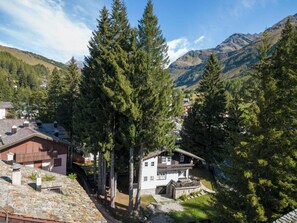A mountain village with traditional houses, surrounded by dense forests and mountains.