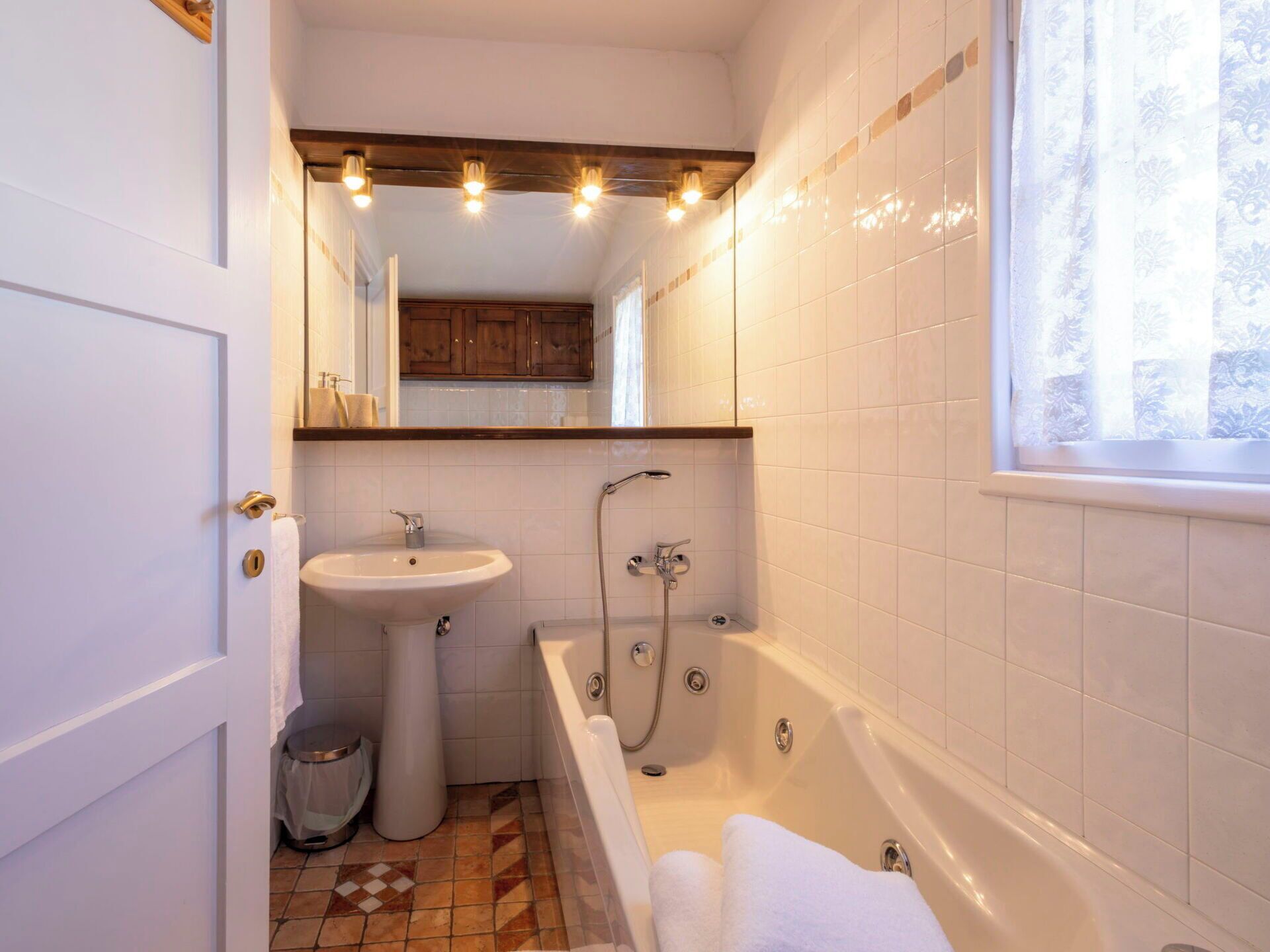 Ein Badezimmer mit Waschbecken, Badewanne und einem Fenster mit Vorhängen.