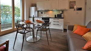 Een moderne keuken met witte kasten, een eettafel met stoelen en een uitzicht door grote ramen.