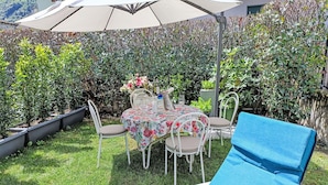 Een terras met een tafel, stoelen en een blauwe loungestoel.