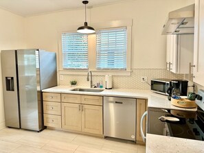 Une cuisine moderne équipée d’appareils électroménagers en acier inoxydable, d’un lave-vaisselle et d’un four à micro-ondes.