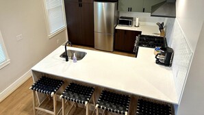 Una cocina compacta con un refrigerador de acero inoxidable, un microondas y una estufa a gas.