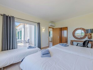 Habitación de hotel con dos camas, un escritorio, una silla, un espejo grande y vistas al exterior.