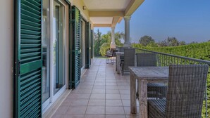 A covered balcony with outdoor furniture, a tiled floor, and a view of greenery. - Wonderful private villa for 10 guests with WIFI, A/C, private pool, TV and terrace (Albufeira)