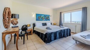 A hotel room with two beds, a desk, a chair, a large window with a view, and a painting on the wall. - Wonderful private villa for 10 guests with WIFI, A/C, private pool, TV and terrace (Albufeira)