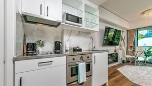 A modern kitchen with a built-in microwave, oven, and stove. There is a dining area with a table and chairs, and a large window offering a view. - Viaduct`s Hidden Gem (Auckland)