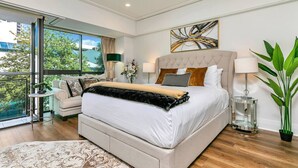 A modern bedroom with a large bed, a sofa, a side table, a floor lamp, and a potted plant. - Viaduct`s Hidden Gem (Auckland)