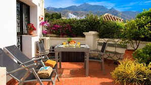 Une terrasse avec une table préparée pour le petit-déjeuner, des chaises d’extérieur et des plantes en pot.