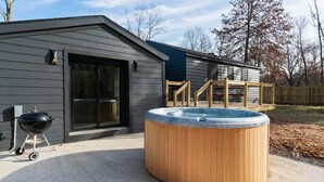 A modern house with a hot tub, a barbecue grill, and a wooden deck.