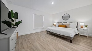 Een moderne slaapkamer met een bed, nachtkastjes, een spiegel en een plant.