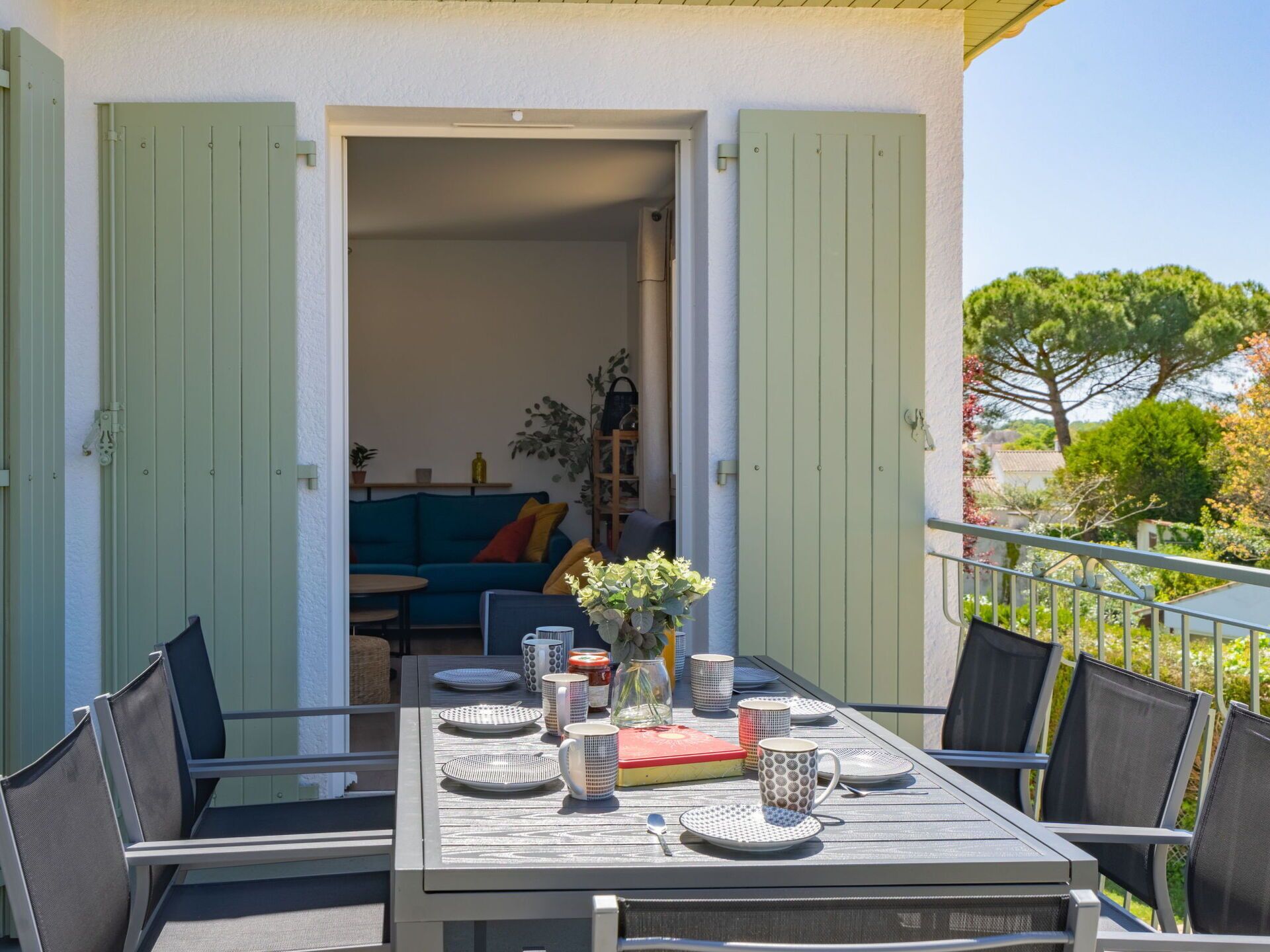 An outdoor dining area with a table set for four, surrounded by chairs.