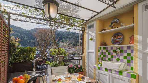 Een balkon met een ontbijtje gedekt, een stadszicht en een betegelde spatwand.