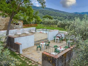 A stone patio with outdoor seating, a pool, and a view of the surrounding hills.