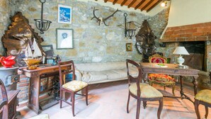 Un comedor rústico con paredes de piedra, vigas de madera y una chimenea.