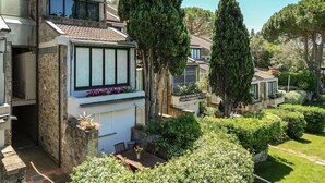 A modern house with a stone facade, large windows, and a well-maintained garden with various plants and a patio area. - Cosy apartment for 6 people with pool, WIFI, TV, terrace and pets allowed (Castiglione Della Pescaia)