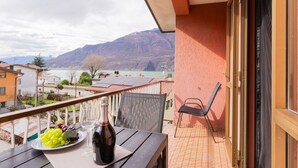 Un balcon avec une table dressée pour deux personnes, une bouteille de vin et une assiette de raisins.