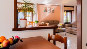 Un coin repas avec une table en bois, des chaises, une plante en pot et un panier de fruits.