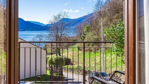 A balcony with a view of a lake, mountains, and a clear sky.