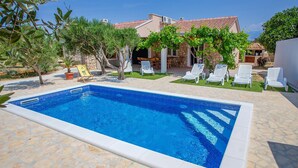 A rectangular swimming pool with a stone tiled deck surrounding it. - Gorgeous home in Novalja (Novalja)