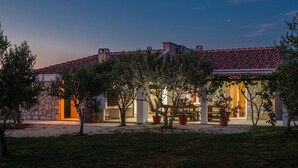 A building with a tiled roof, stone walls, and outdoor seating. - Gorgeous home in Novalja (Novalja)
