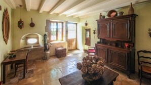 A rustic kitchen with a wooden table, a vase of dried flowers, and a large cabinet.