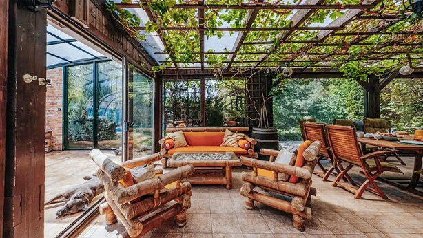Une terrasse extérieure avec un banc en bois, un canapé rembourré et une table à manger.