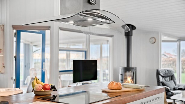 A modern kitchen with a built-in stove, a large window, and a view of a fireplace. - Cozy home in Sjølund with sauna (Sjølund)