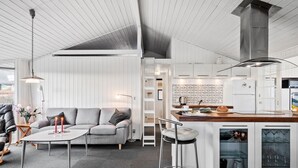 A modern kitchen with white cabinetry, a wooden island, and a built-in wine fridge. - Cozy home in Sjølund with sauna (Sjølund)