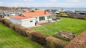A residential area with houses, a grassy yard, and a body of water in the background. - Cozy home in Sjølund with sauna (Sjølund)
