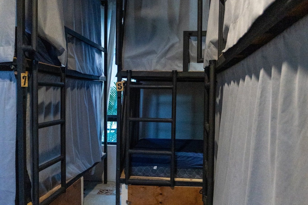 A corridor with bunk beds, a fan, and a window.
