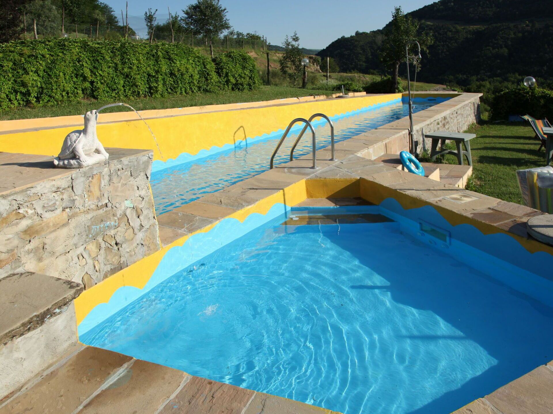 Une piscine avec un mur en pierre et une statue.