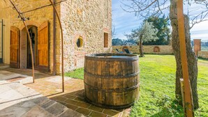 A stone building with wooden doors and a barrel in the courtyard. - Beautiful private villa for 3 people with A/C, WIFI, patio and panoramic view (Montescudaio)